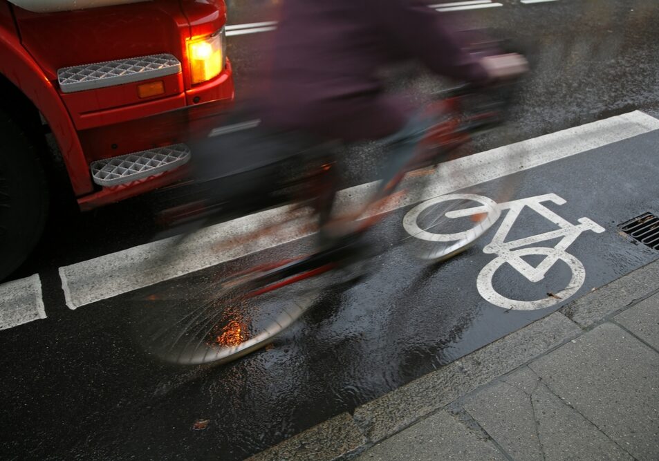 un camion passe à hauteur d'un cycliste sur une piste cyclable