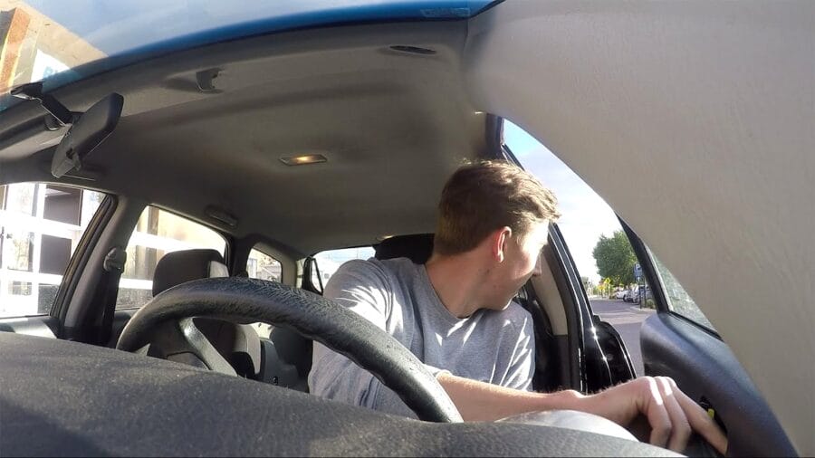 Un conducteur vérifie que la voie est libre avant de quitter son véhicule, en utilisant la technique de la poignée hollandaise.