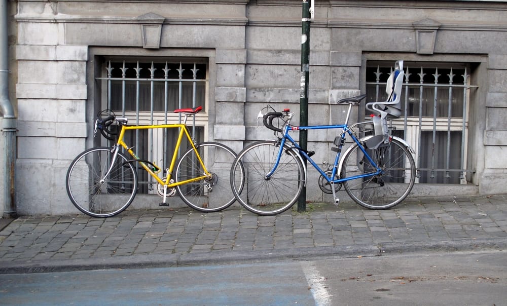 Deux vélos stationnés sur le trottoir, le long d'une façade