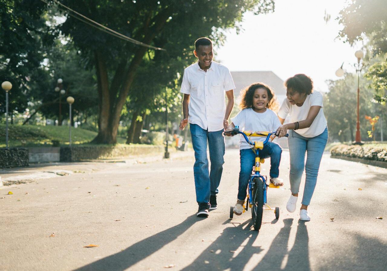 Deux parents apprennent à leur enfant à faire du vélo
